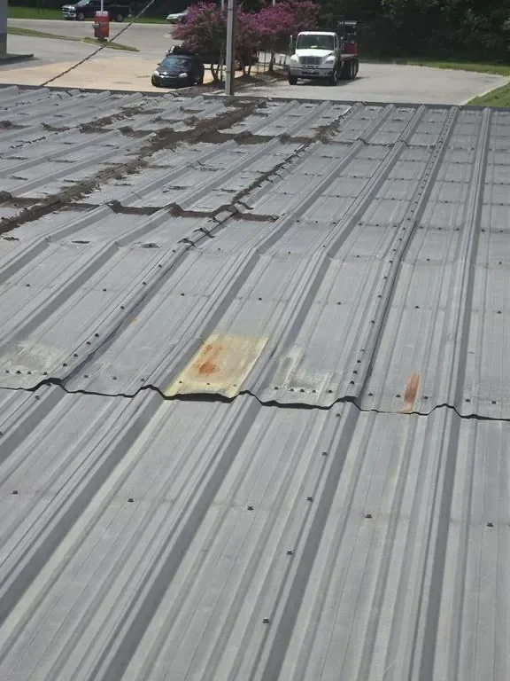 Aged commercial metal roof with debris lines along the panels before coating restoration