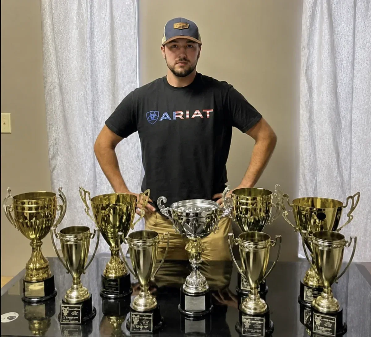 Josh standing behind a table of his competition trophies