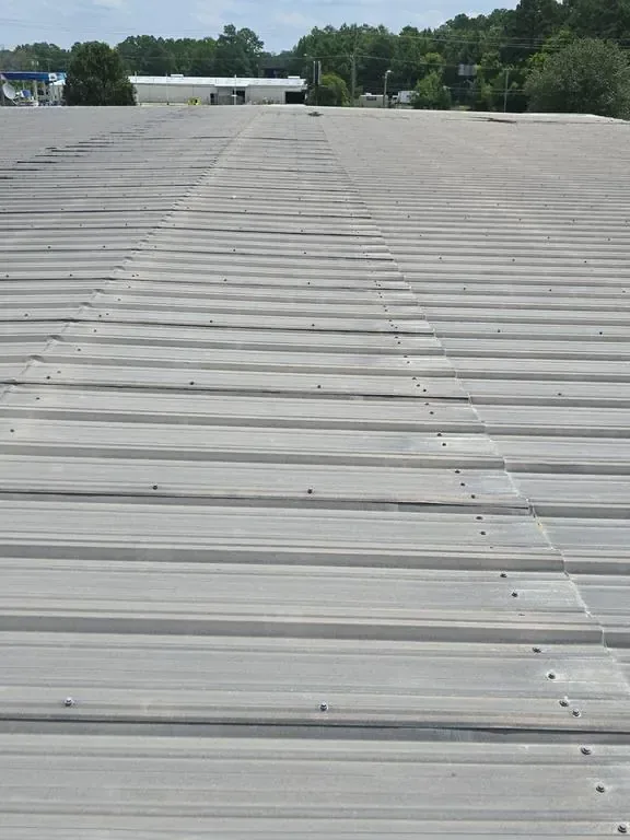 Corrugated metal commercial roof viewed down the panel ribs before retrofit work