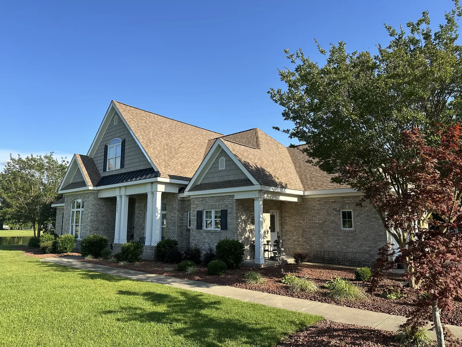 Corner view of a finished golden tan architectural shingle roof by Carolina Trophy Roofs in evening light