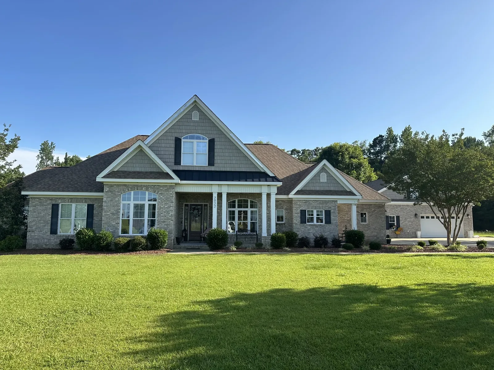 Front elevation of a brick and siding home with a new golden tan shingle roof