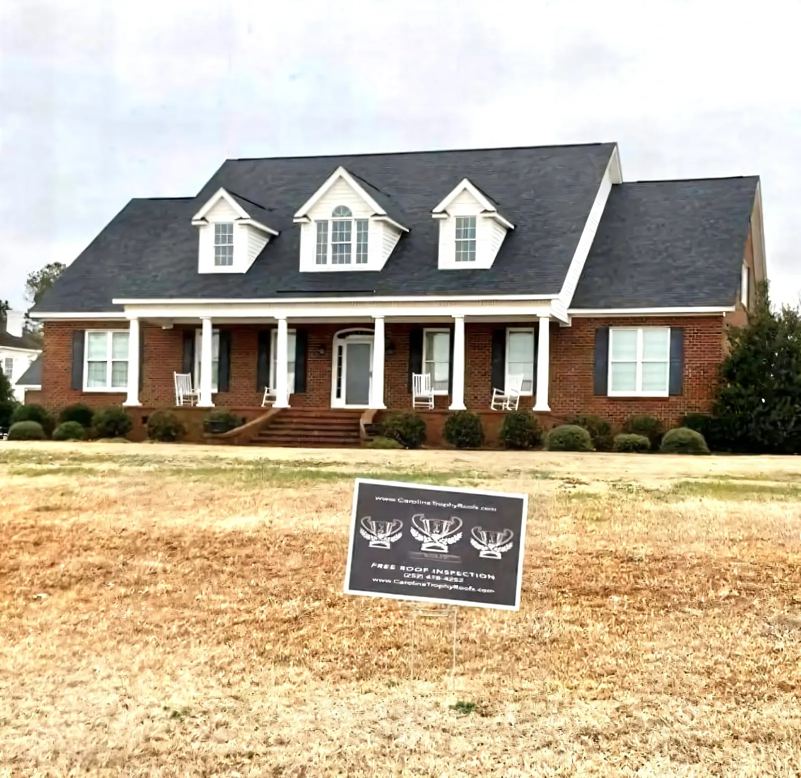 Brick colonial home with a new dark charcoal architectural shingle roof installed by Carolina Trophy Roofs