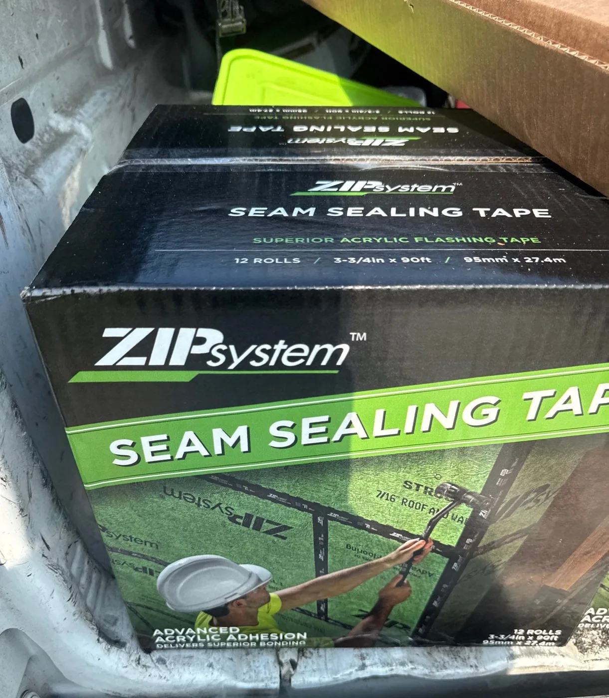A case of ZIP System acrylic seam sealing tape in the bed of a work truck on a Carolina Trophy Roofs job site
