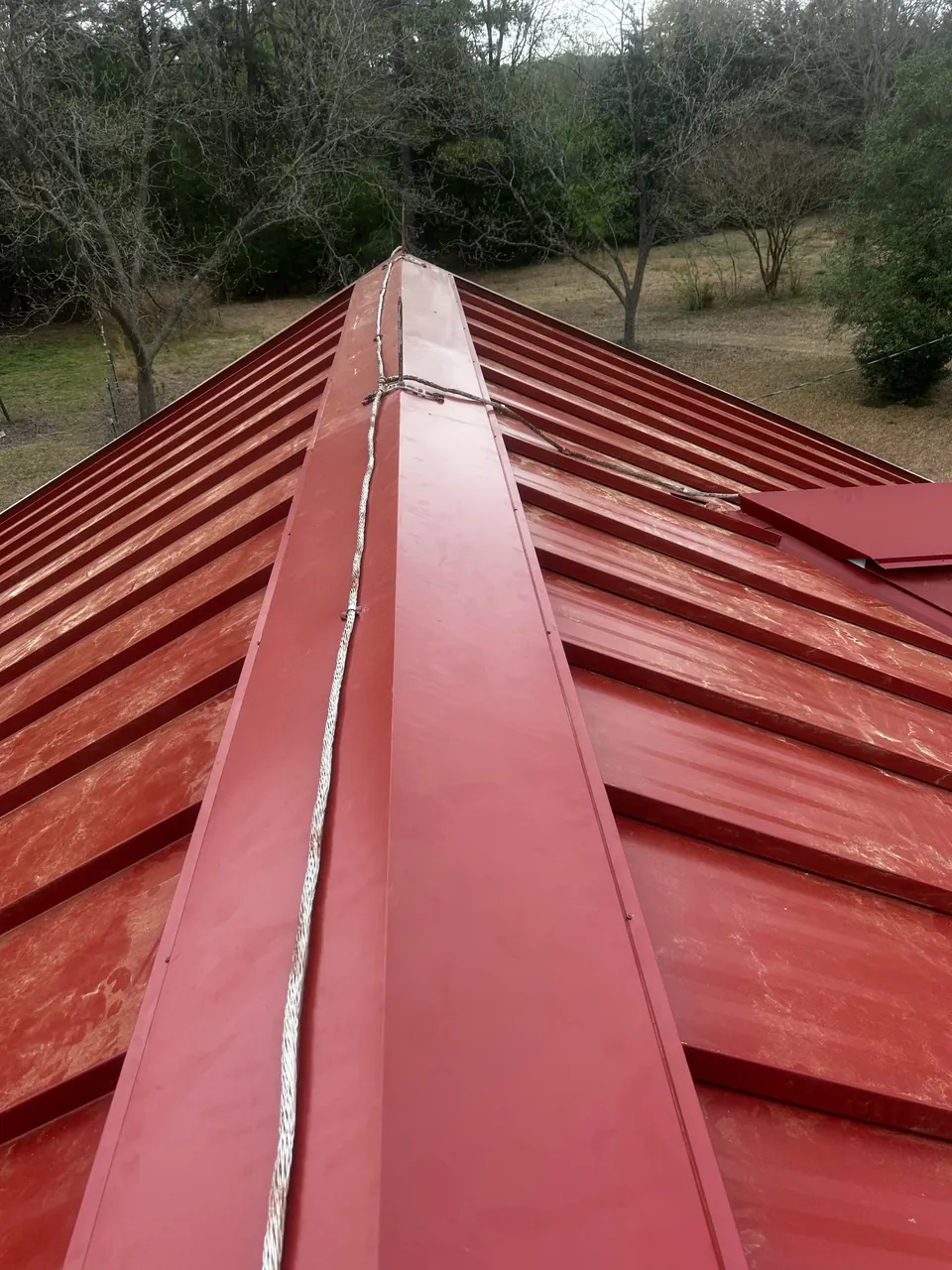 Ridge cap on a new red standing-seam metal roof in Benson, NC, seen from the peak