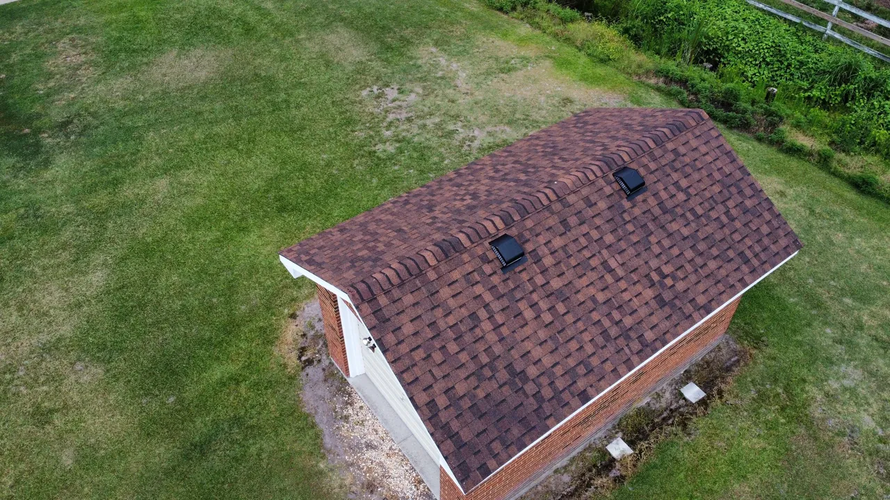 Drone view of a brick outbuilding in Edenton, NC with a new brown shingle roof matching the house
