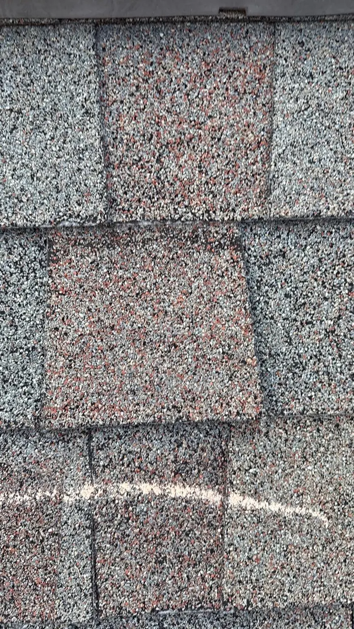 Close-up of shingles with a chalk mark on a damaged shingle during a storm inspection in Goldsboro, NC