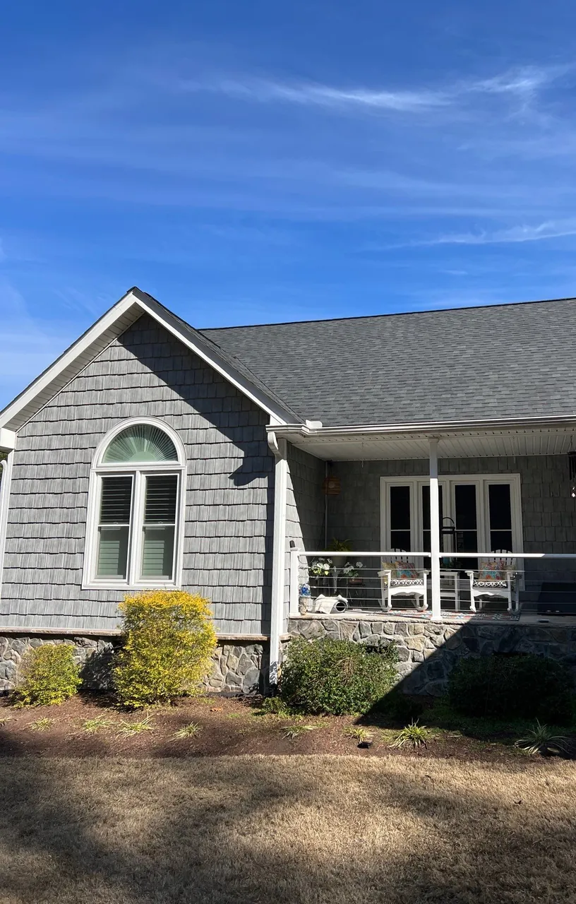 Covered porch with stone skirting and an arched window under a new charcoal shingle roof in Goldsboro, NC