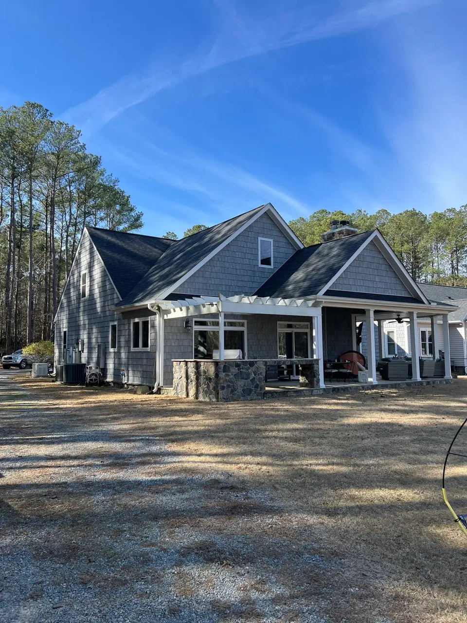 Gray shake-sided home in Goldsboro, NC with a new charcoal architectural shingle roof and a covered patio under a blue sky