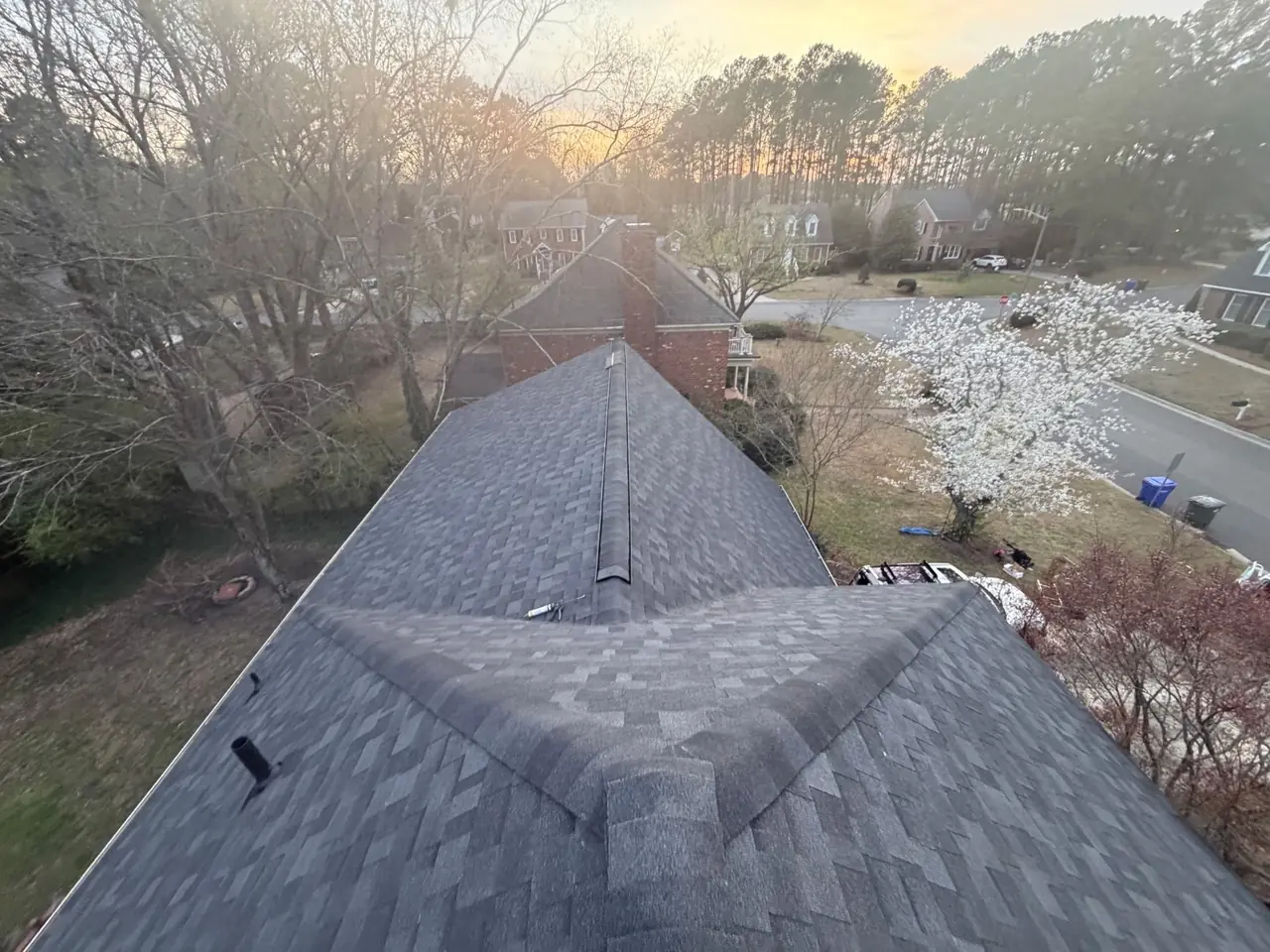 New charcoal architectural shingle roof on a Greenville, NC home, photographed along the ridge at sunset