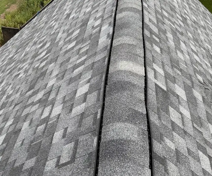 Ridge cap shingles running up a hip on a new gray architectural shingle roof in Greenville, NC