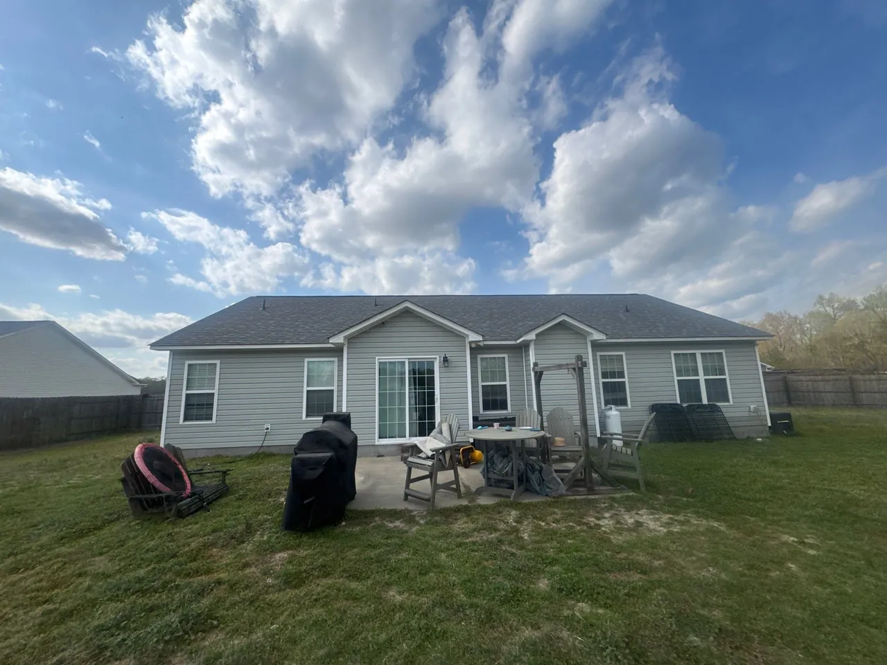 Rear of a ranch home in Richlands, NC with a new gray architectural shingle roof under a cloudy blue sky