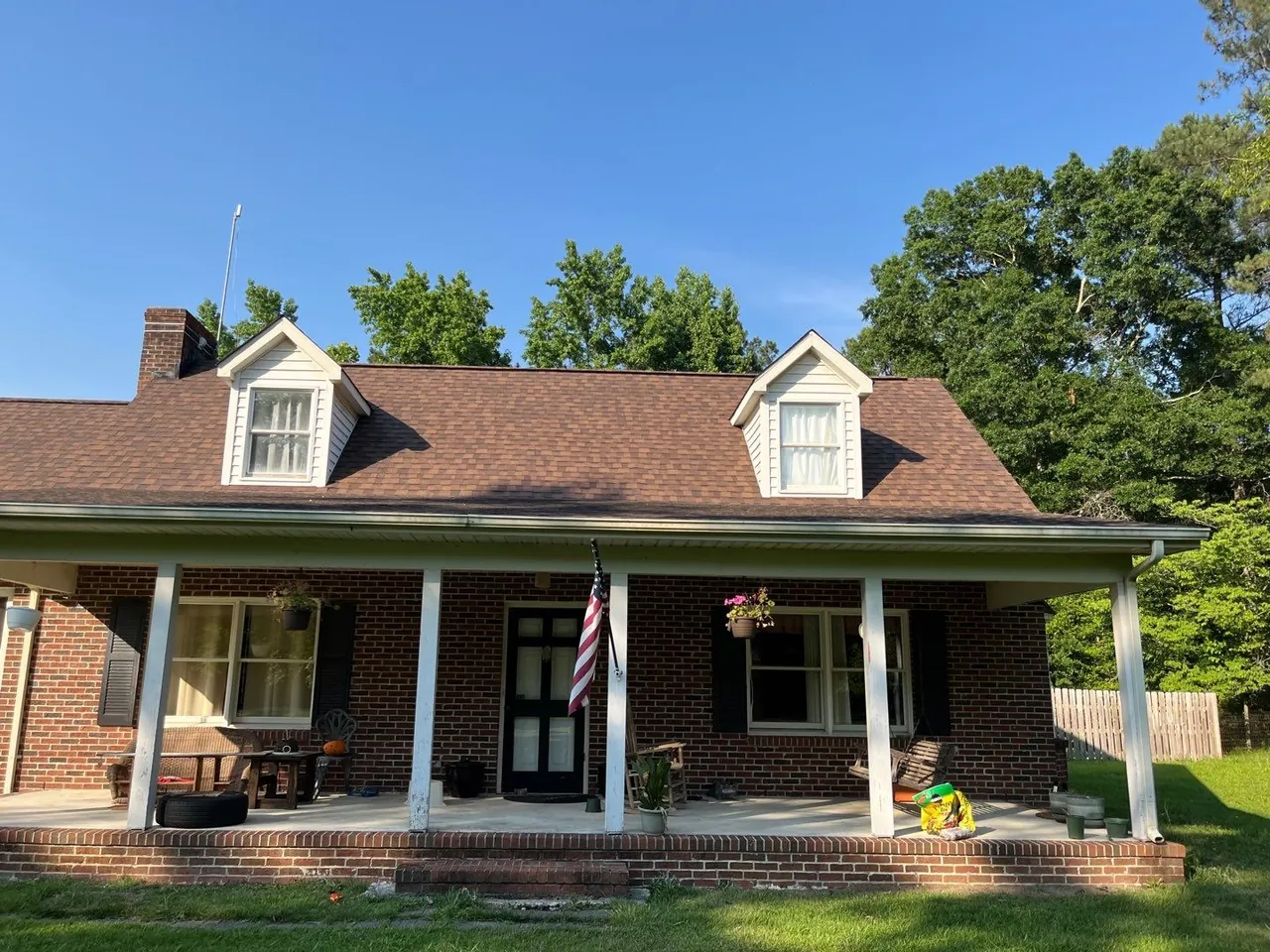 Brick Cape Cod home in Kinston, NC with two dormers, a long front porch and a new brown architectural shingle roof