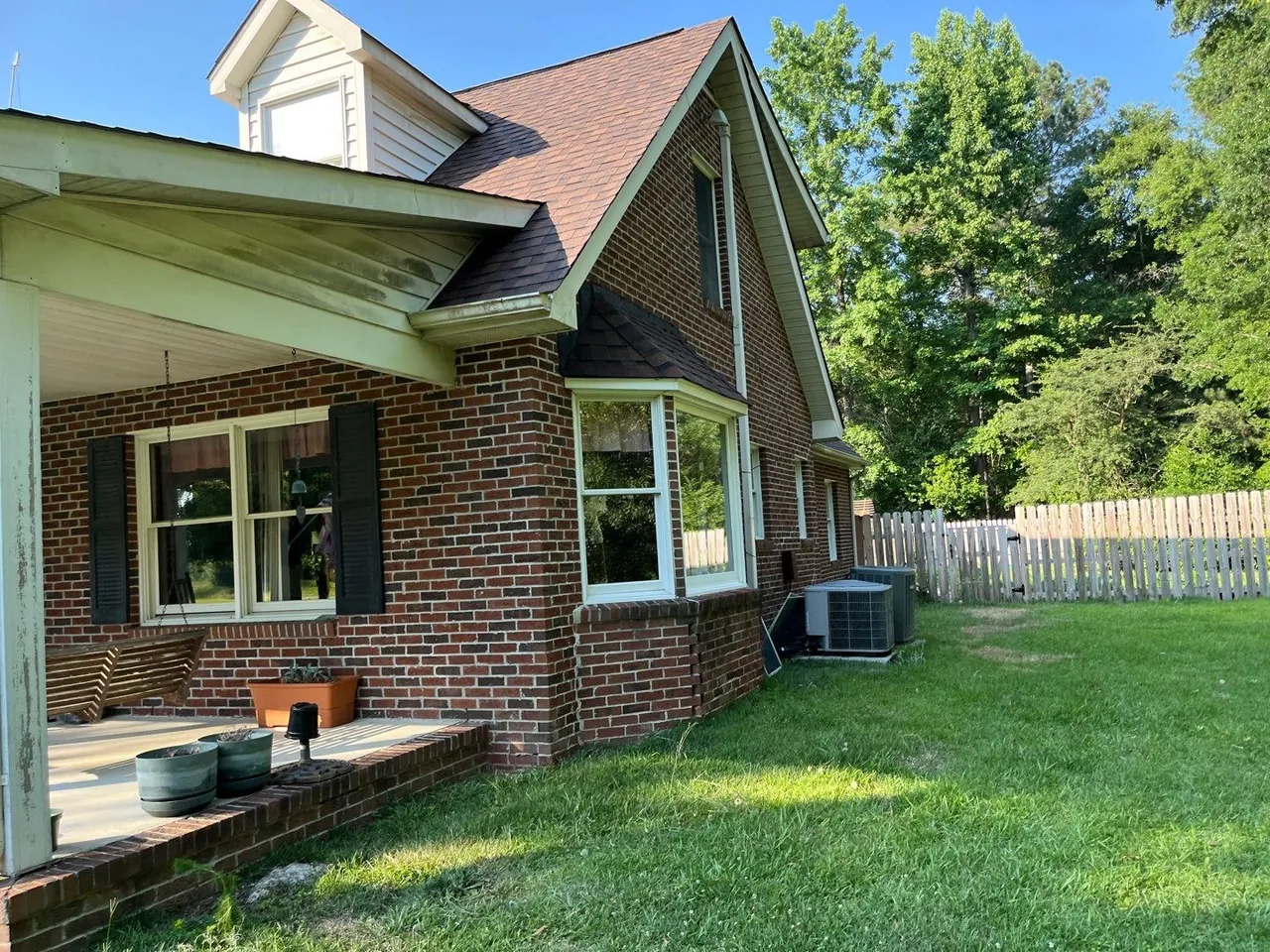 Side gable and bay window under a new brown shingle roof on a brick home in Kinston, NC