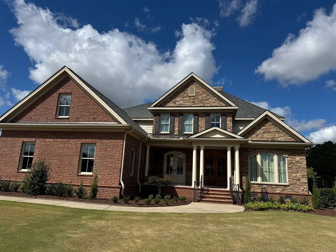 Brick-and-stone two-story home in Snow Hill, NC with a new gray architectural shingle roof under a blue sky