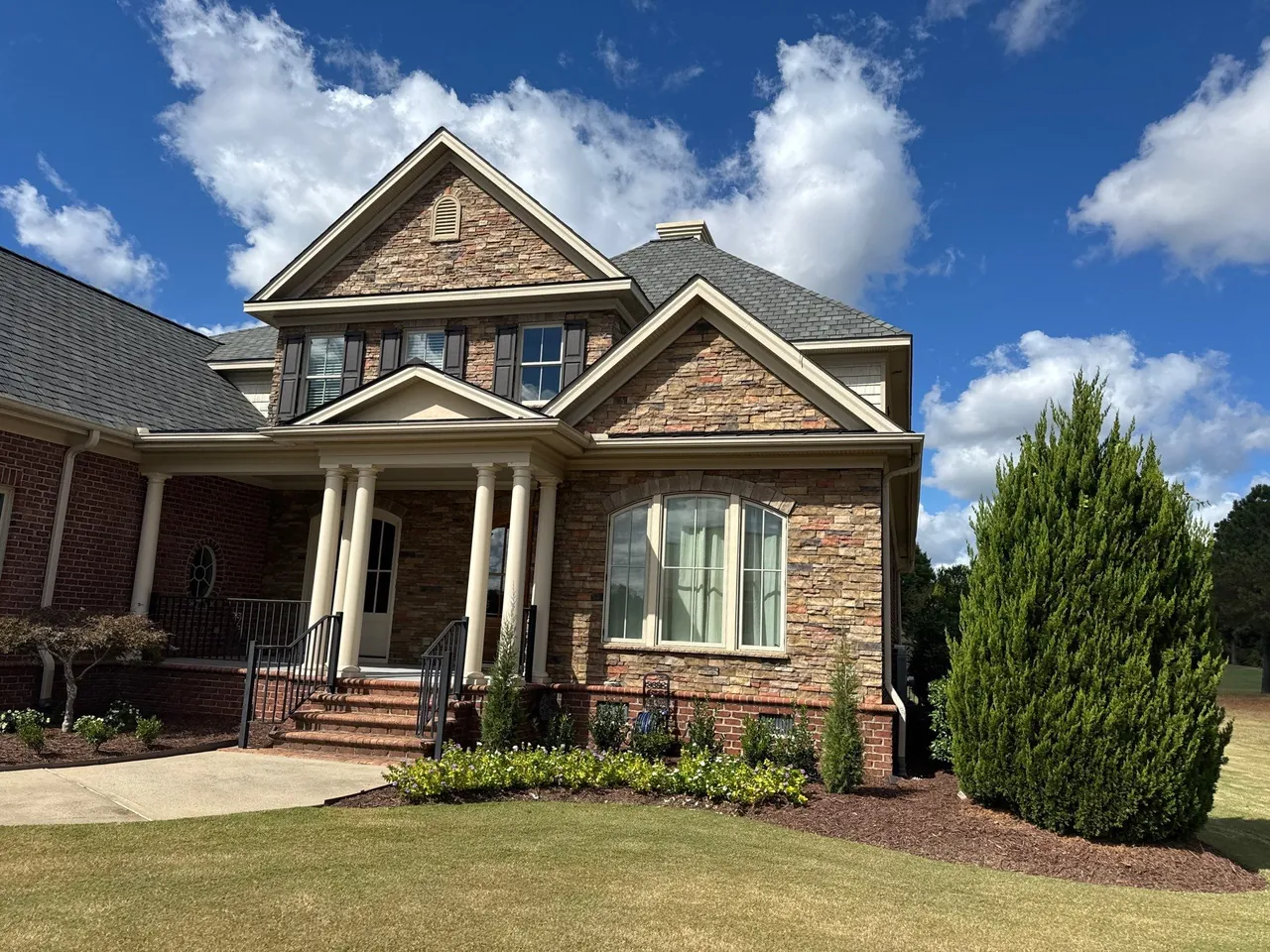 Stone-faced gable and columned entry under a new gray shingle roof on a home in Snow Hill, NC