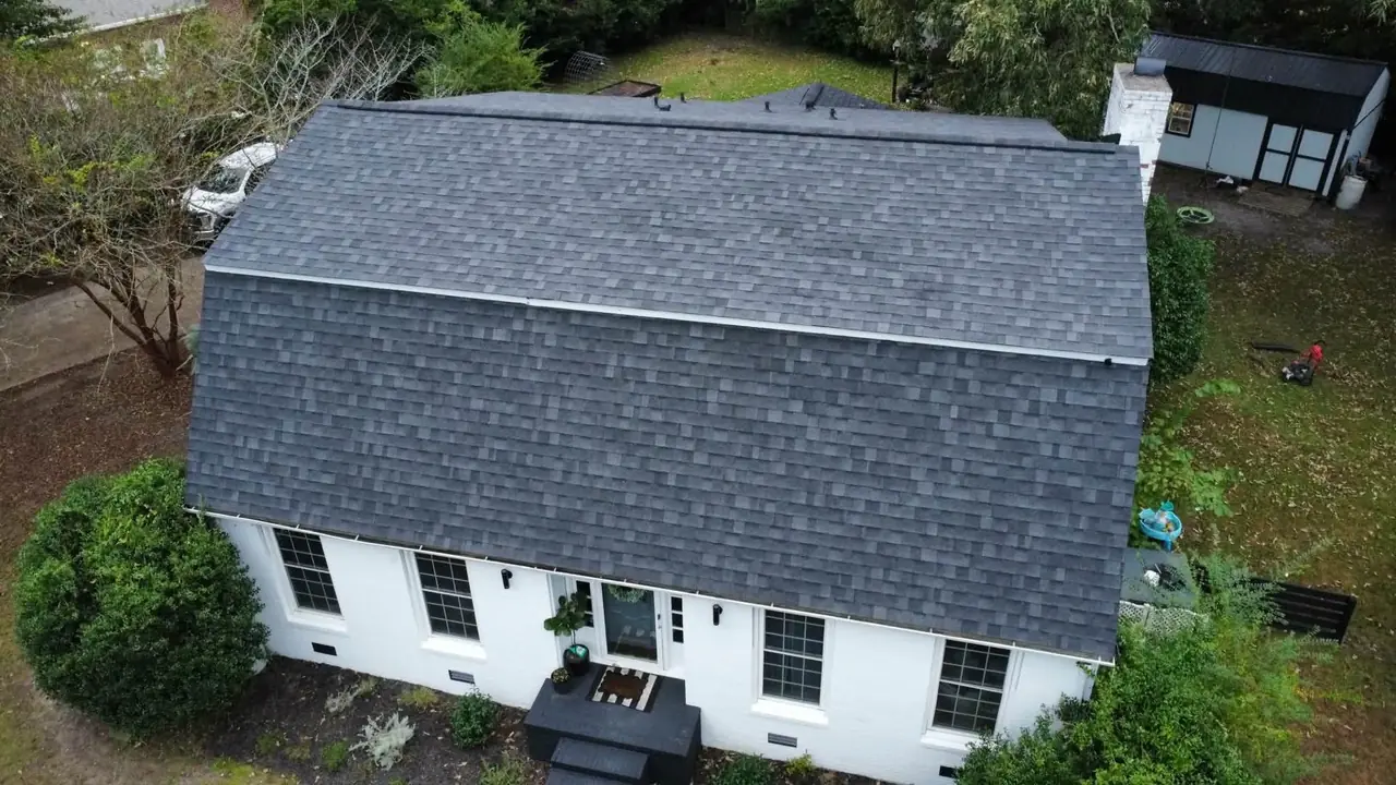 Drone view of a new charcoal architectural shingle gambrel roof on a white brick home in New Bern, NC