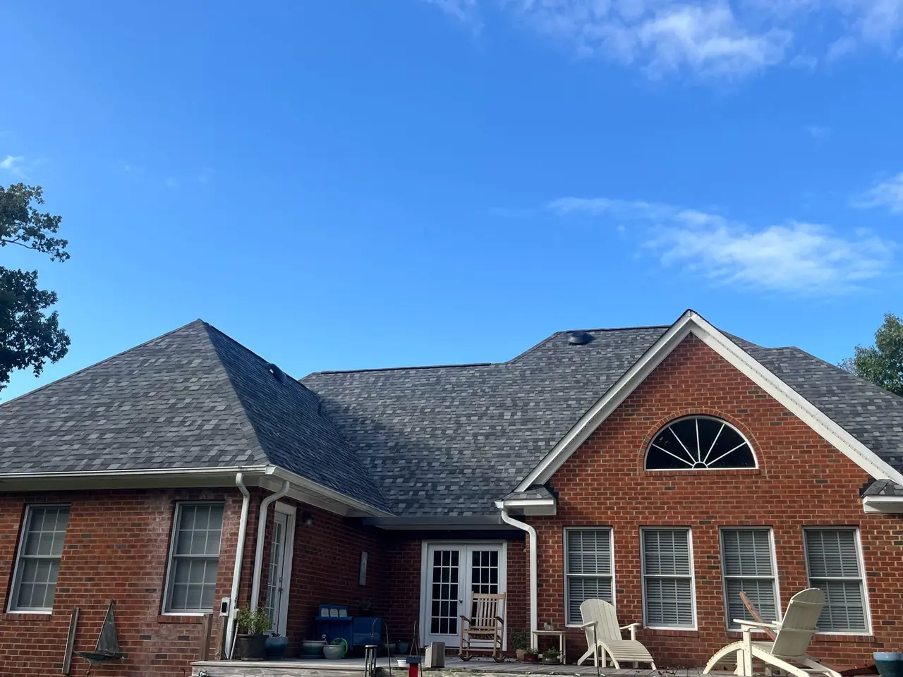 Rear of a brick home in Trent Woods, NC showing a new charcoal shingle hip-and-gable roof