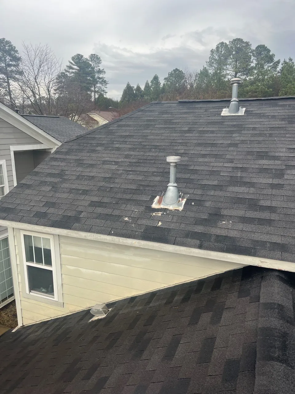 Worn, streaked shingles and metal vent stacks on the upper roof of a Raleigh, NC home, photographed during an inspection