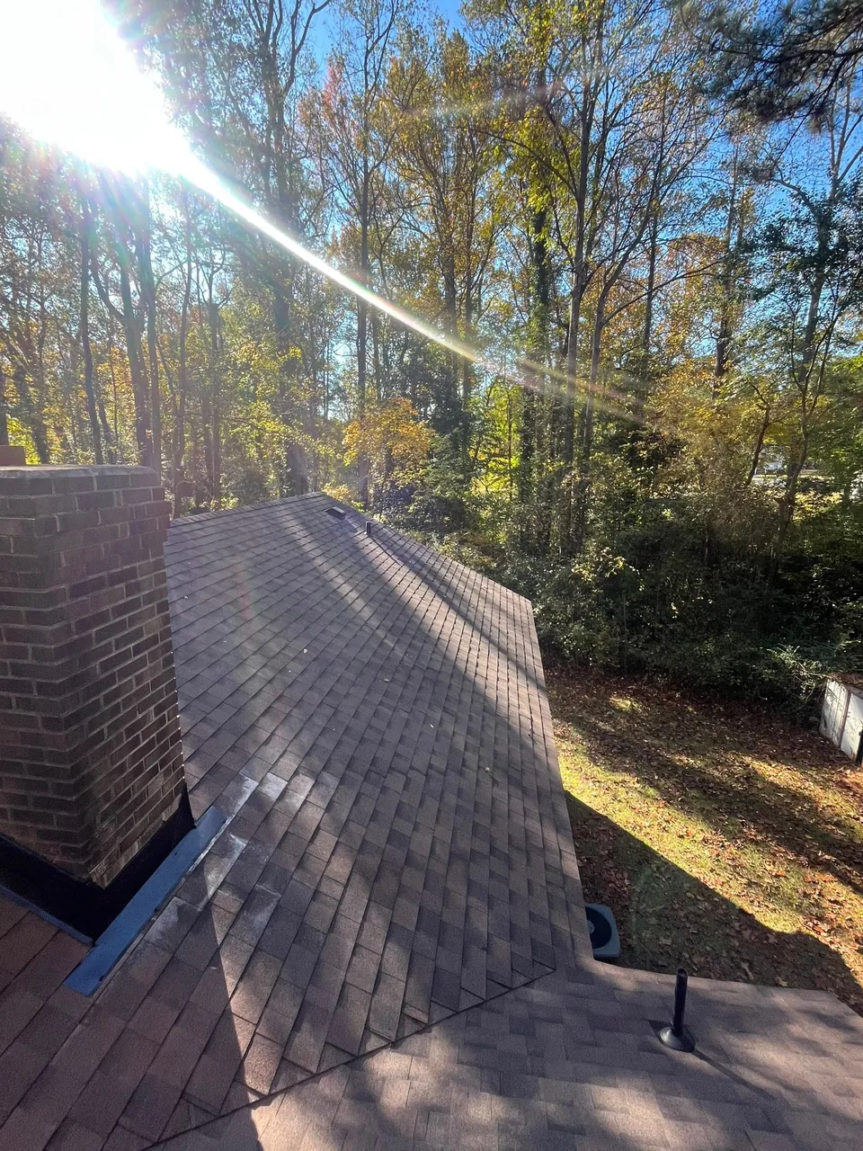 Metal flashing along the side of a brick chimney on a new brown shingle roof in Roanoke Rapids, NC