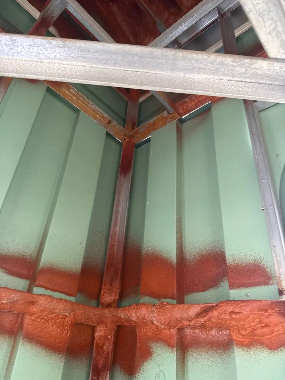 Steel framing and green metal panels inside a church steeple in Nashville, NC, with sealant along the panel joints
