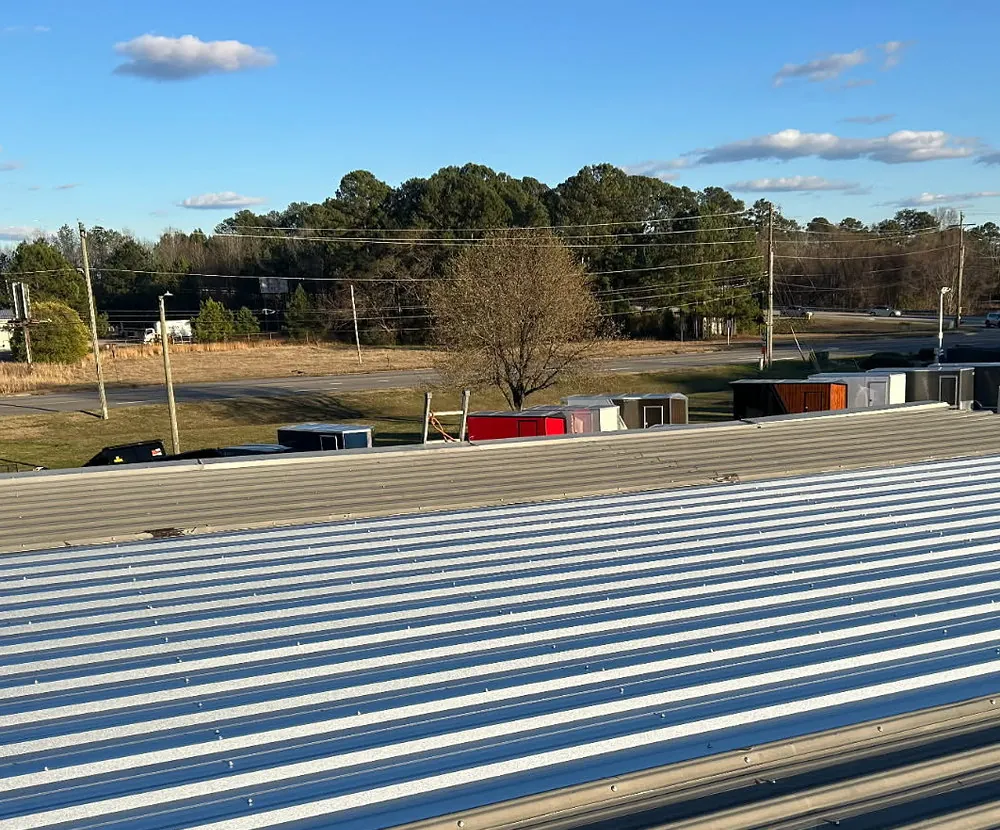New metal roof panels running across a low-slope commercial building roof in Rocky Mount, NC, under a blue sky