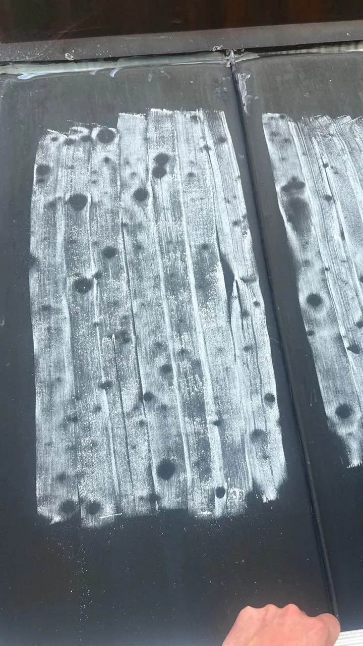 Hail dents outlined in white chalk on a dark metal roof section during a storm inspection in Rocky Mount, NC