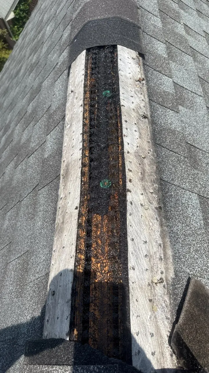 Weathered old ridge vent along the peak of a shingle roof in Rocky Mount, NC, photographed during a storm inspection