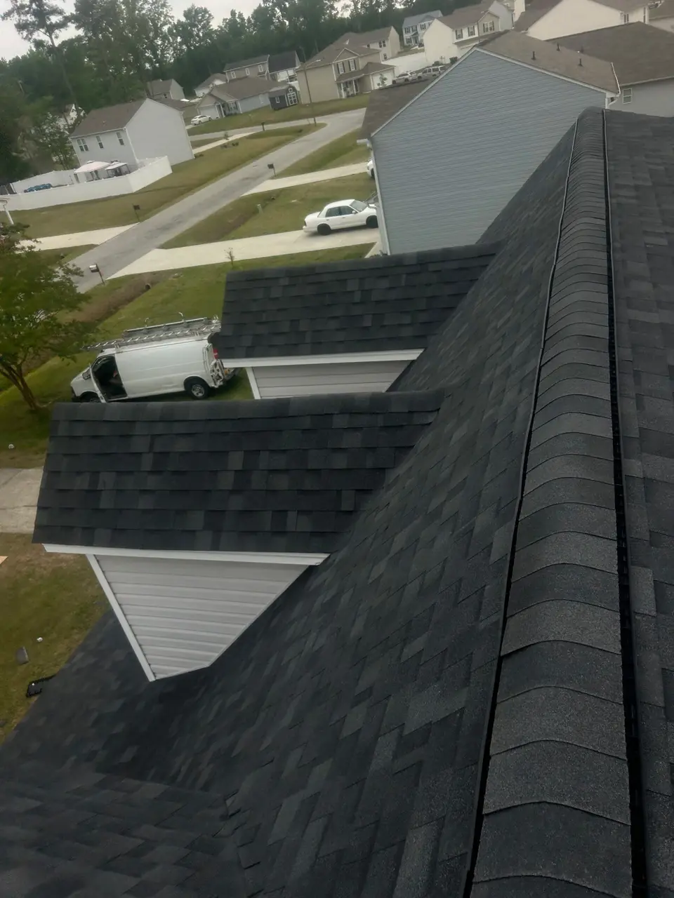 New dark architectural shingles, ridge vent and dormers on a two-story home in Tarboro, NC, seen from the ridge