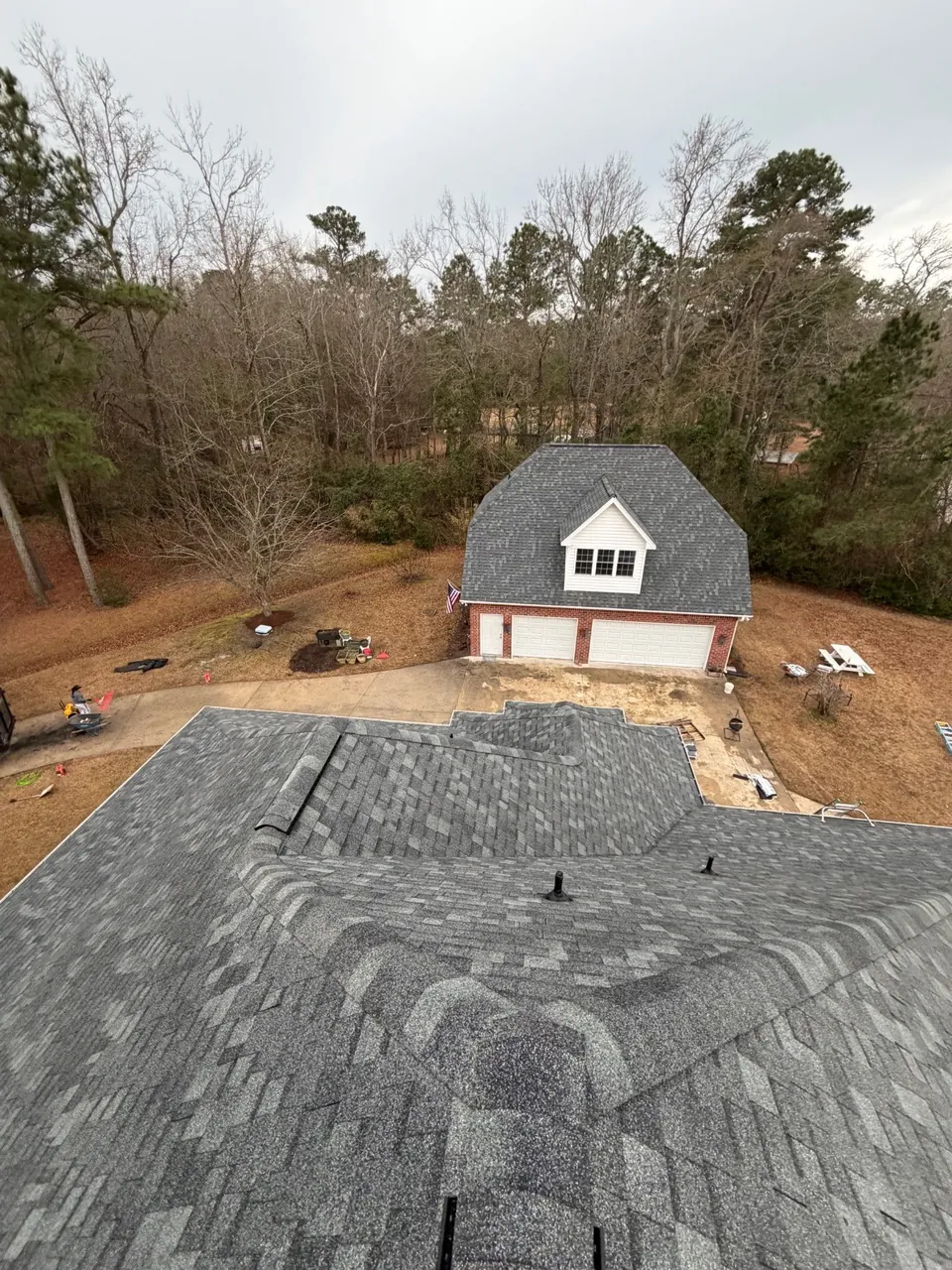 Hips, valleys and roof vents on a new gray shingle roof in Belhaven, NC, with a detached garage beyond