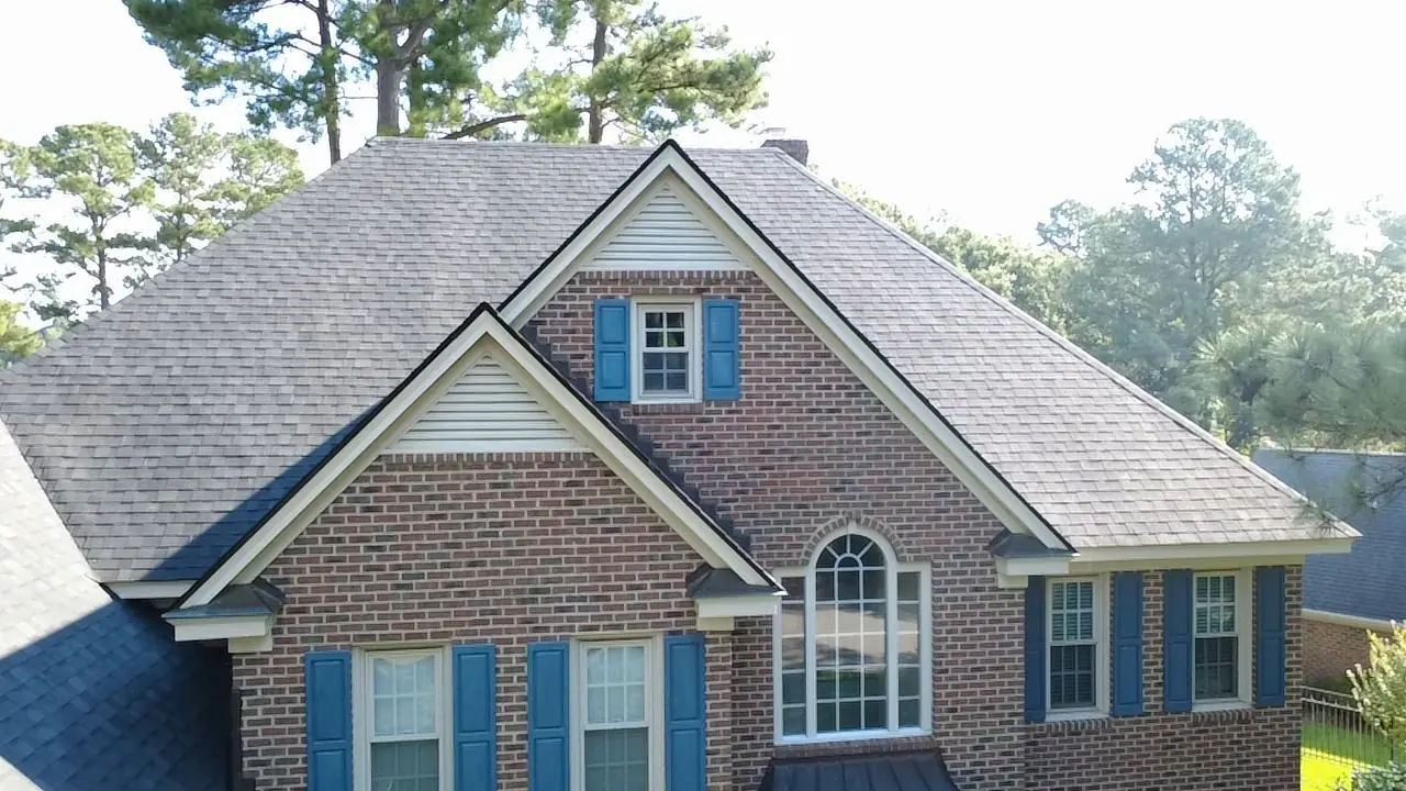 Brick home in Wilson, NC with blue shutters and a new architectural shingle roof, photographed by drone from the front