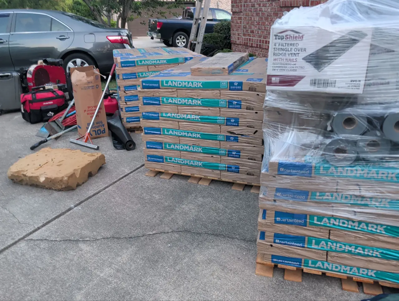 Pallets of CertainTeed Landmark shingles and a box of TopShield filtered ridge vent on a driveway in Wilson, NC