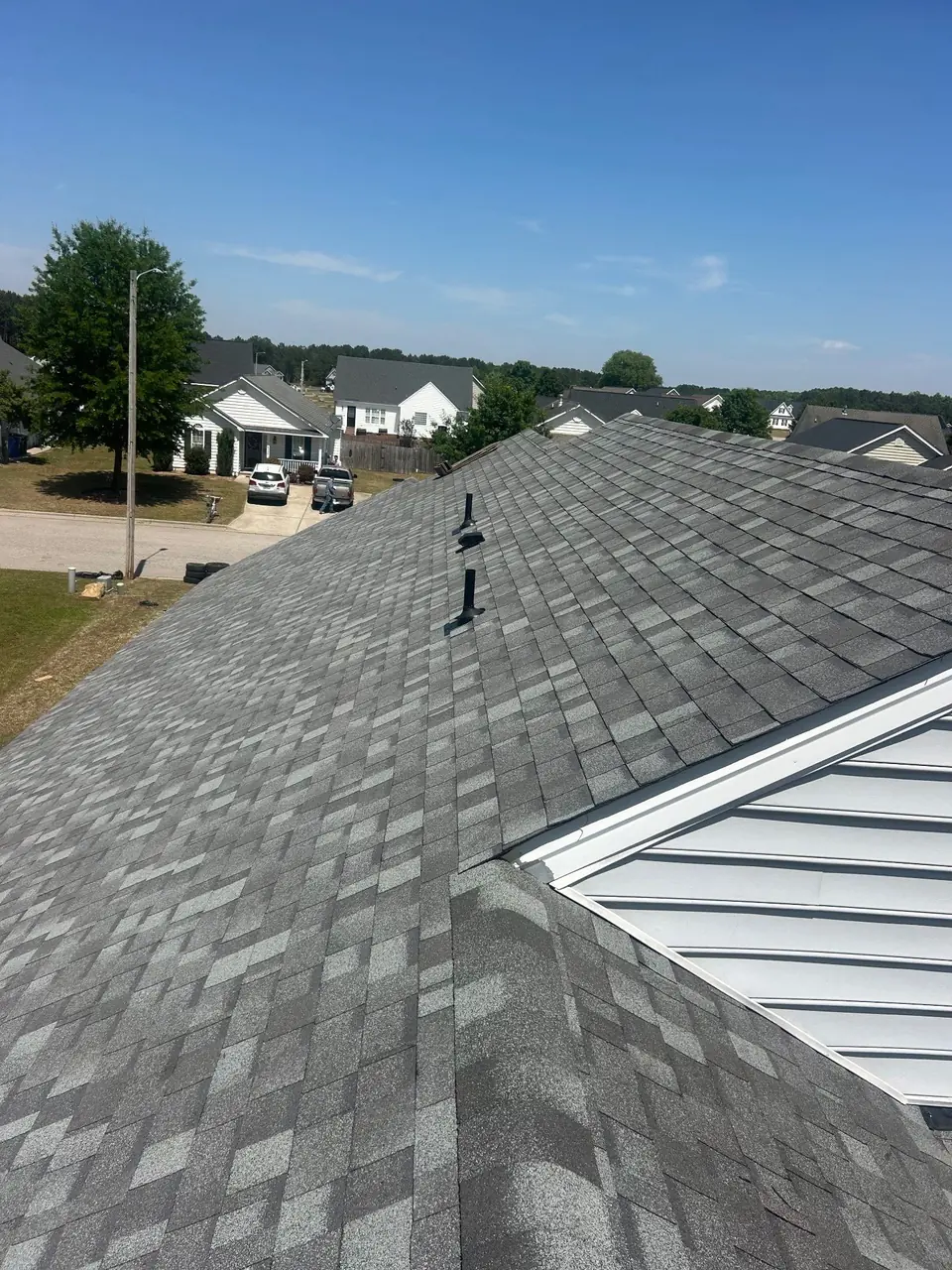 New gray architectural shingles meeting a sided gable on a one-story home in Wilson, NC, with two plumbing vent boots