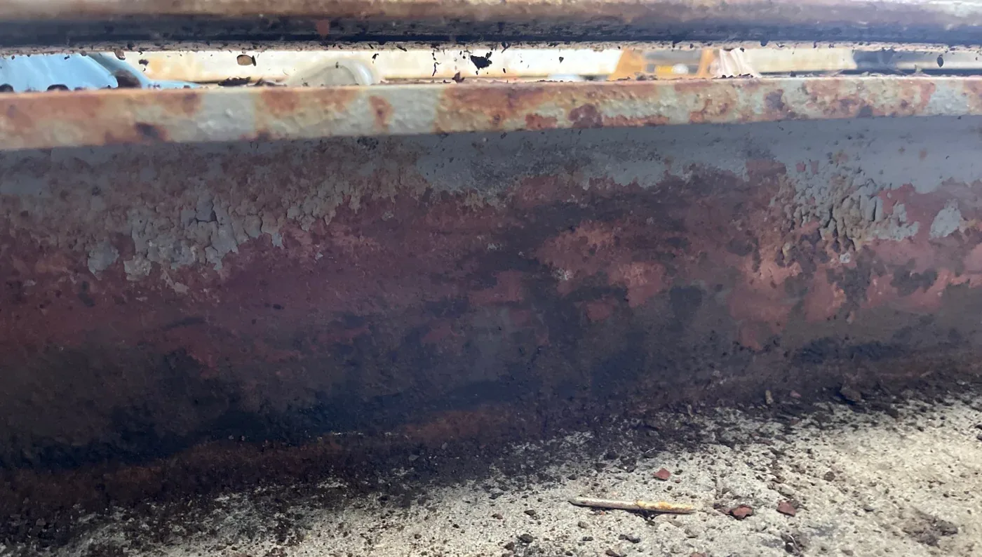 Heavily rusted steel curb running along the edge of a flat metal deck at the base of a church steeple in Eastern North Carolina, before restoration
