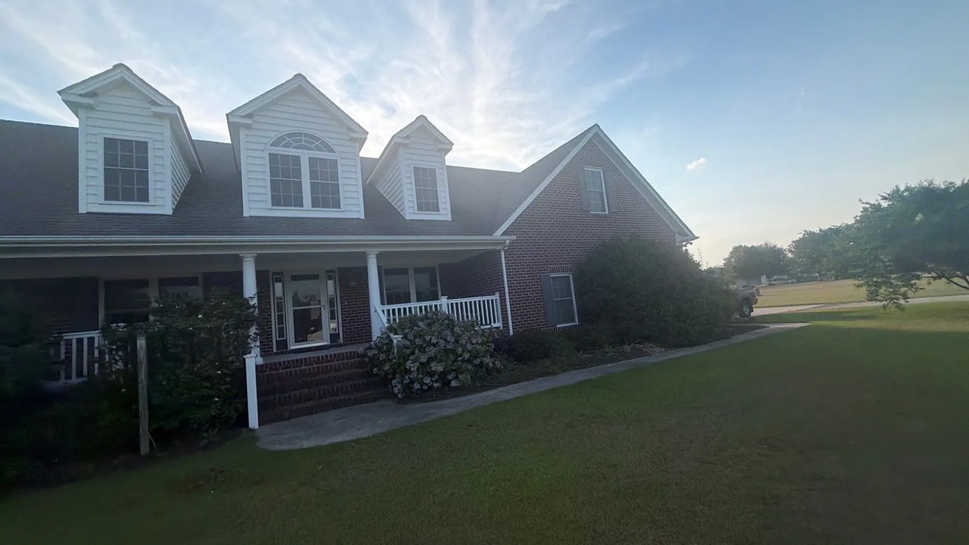 Front elevation of a brick home in Eastern North Carolina with its original weathered asphalt shingle roof, before replacement.