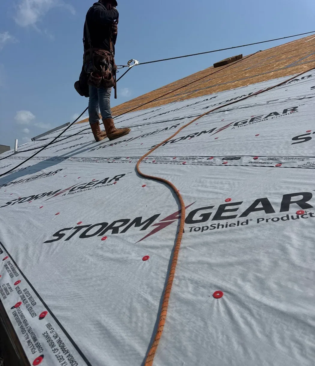 Synthetic underlayment rolled out and cap-nailed across a roof deck on a Carolina Trophy Roofs job in Eastern North Carolina, with the sealed deck still exposed above it