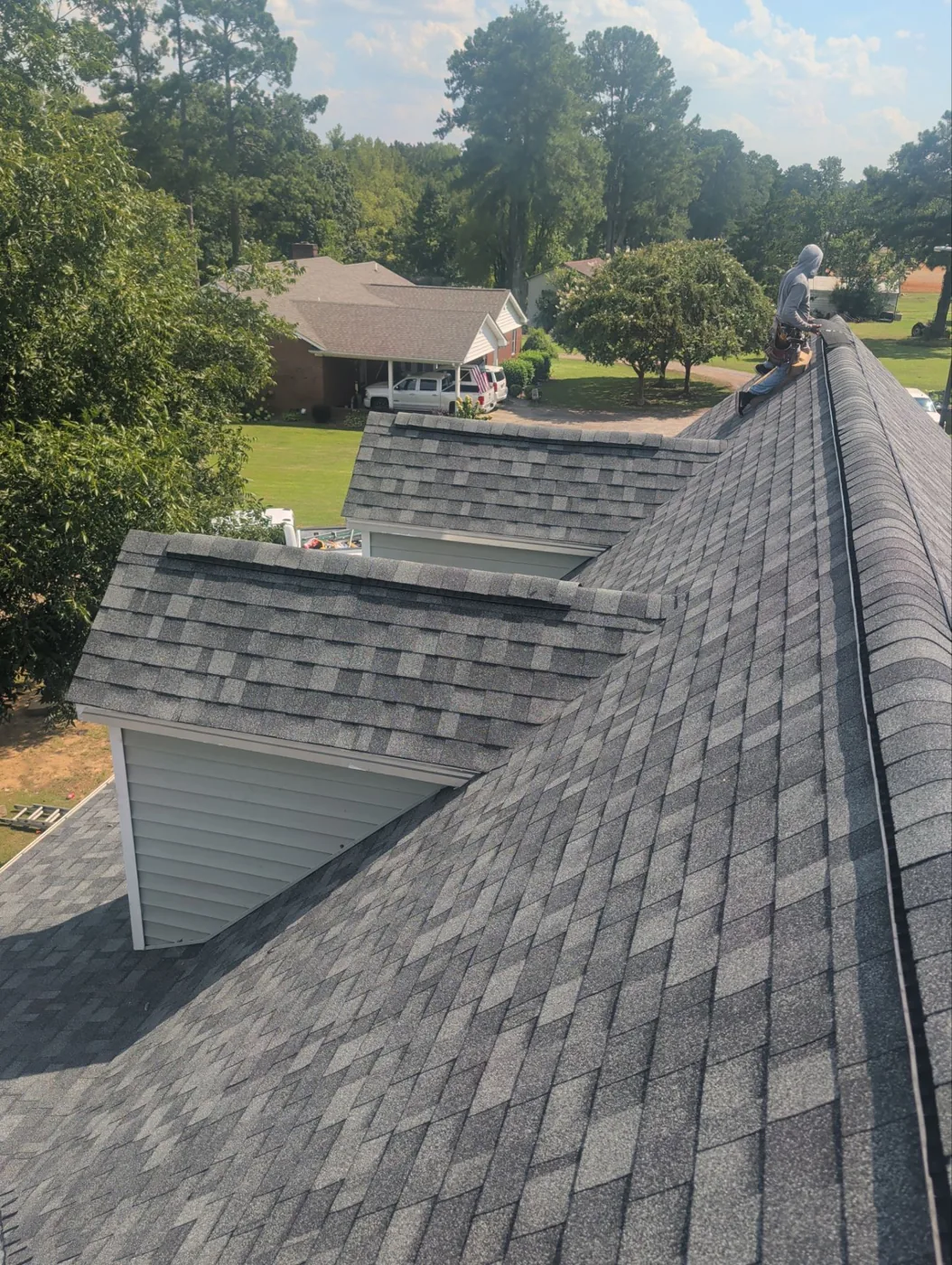 Completed storm-damage roof replacement by Carolina Trophy Roofs, new charcoal architectural shingles across the slopes and dormers with a clean capped ridge