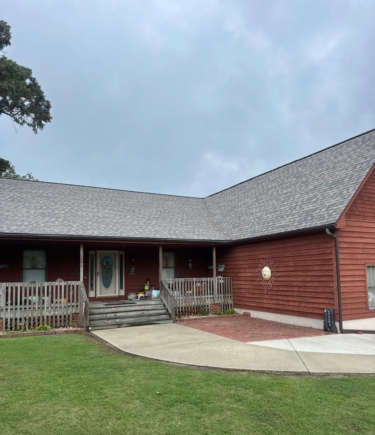 Cool light-gray blend architectural shingles over barn-red wood siding under an overcast sky in Eastern North Carolina