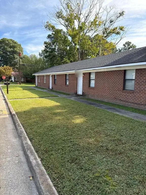 Long single-story red brick building in Rocky Mount, NC with no gutters along the eave, before the gutter job