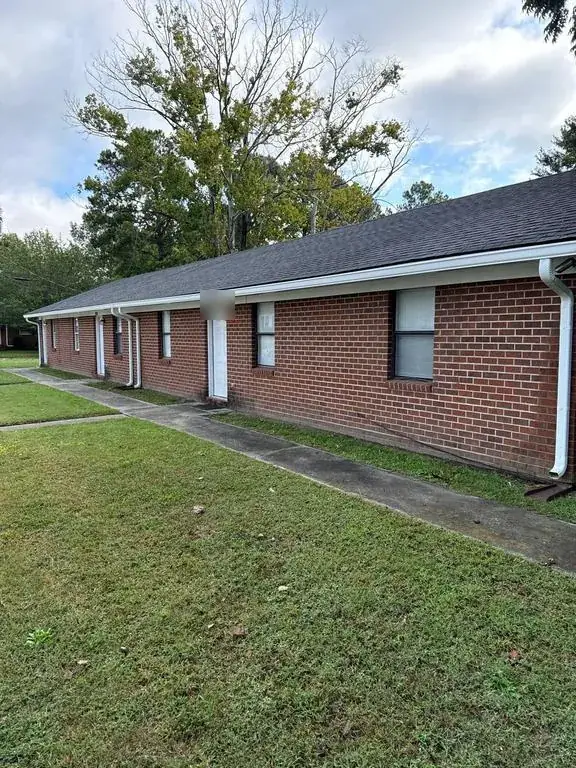 The same brick building in Rocky Mount, NC with new white seamless gutters along the eave and downspouts at the corners